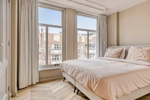 Double bedroom beside tall windows at Splendom Vondelpark